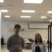 Two students standing next to a fifth block elevator project.